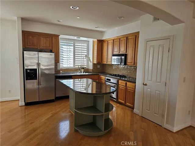 a kitchen with granite countertop a stove a refrigerator and wooden floor