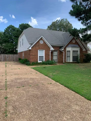 a view of a house next to a yard with big trees