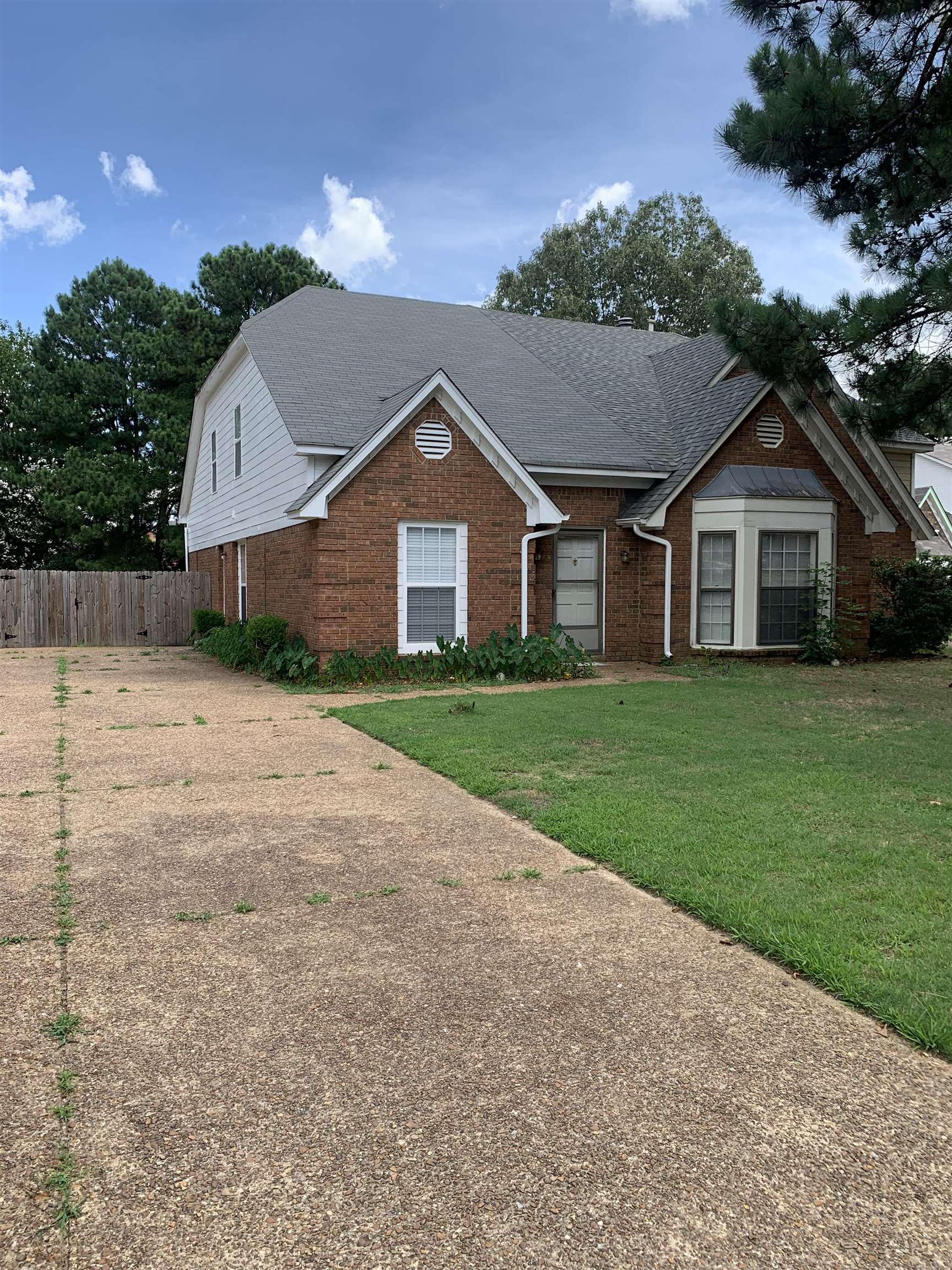 a view of a house next to a yard with big trees