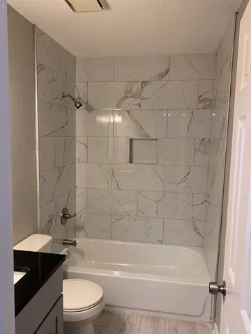 a bathroom with a bathtub shower sink vanity and toilet