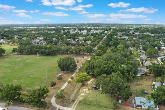 an aerial view of a residential houses with outdoor space and trees