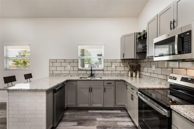 a kitchen with stainless steel appliances granite countertop a sink stove and cabinets