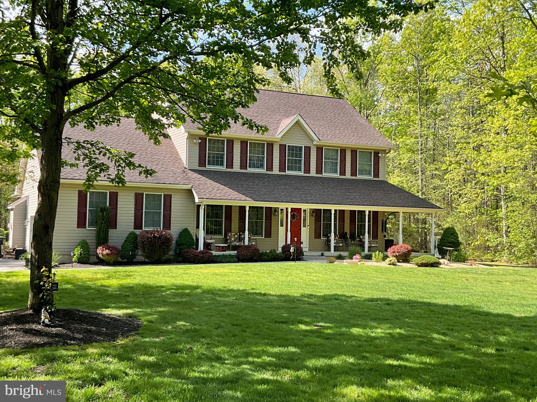a front view of a house with a garden and trees