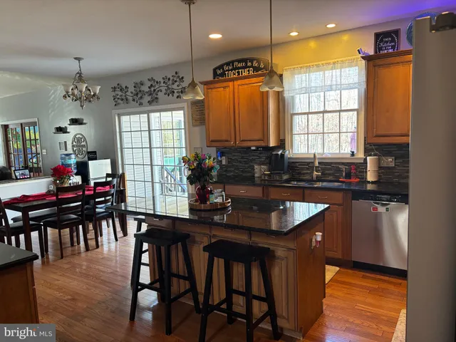 a kitchen with granite countertop a table chairs sink and wooden floor
