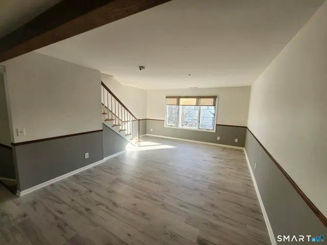 an empty room with wooden floor door and windows