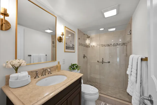 a bathroom with a granite countertop sink a toilet and shower