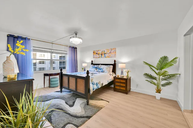 a spacious bedroom with a bed and dresser with wooden floor