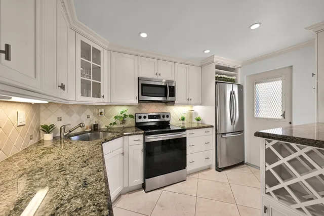 a kitchen with stainless steel appliances granite countertop a stove top oven a sink and a refrigerator