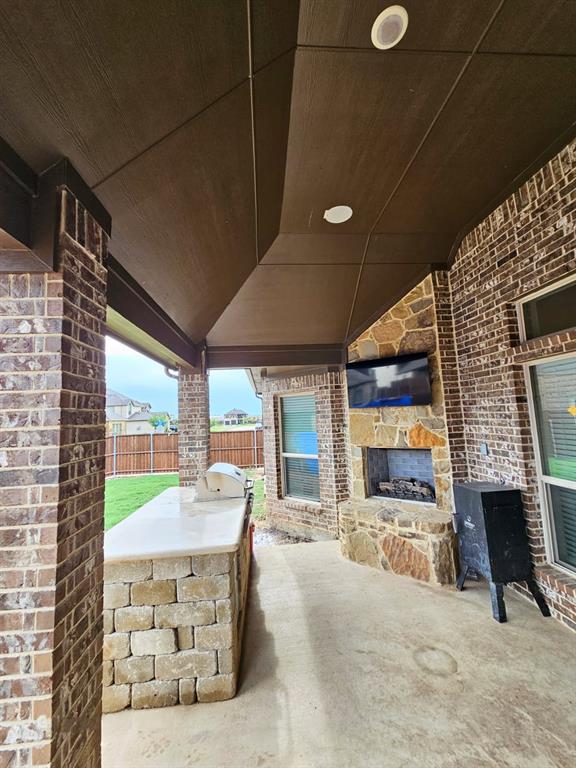 413 Frontier Court Midlothian, TX 76065 - Photo 23 of 26 Covered patio featuring an outdoor kitchen with built-in grill, a stone fireplace, and brick columns