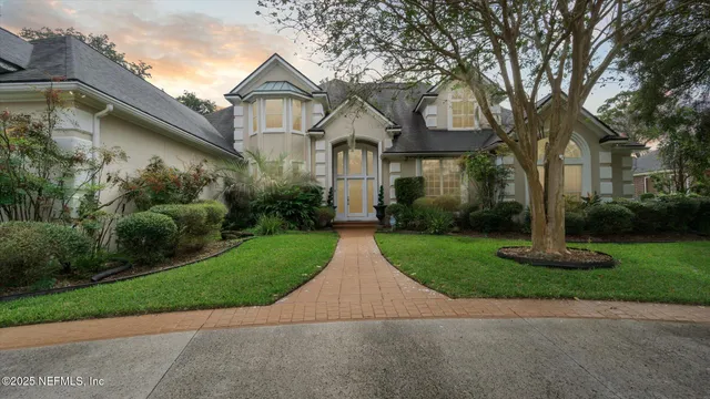 a view of a white house with a yard and large trees
