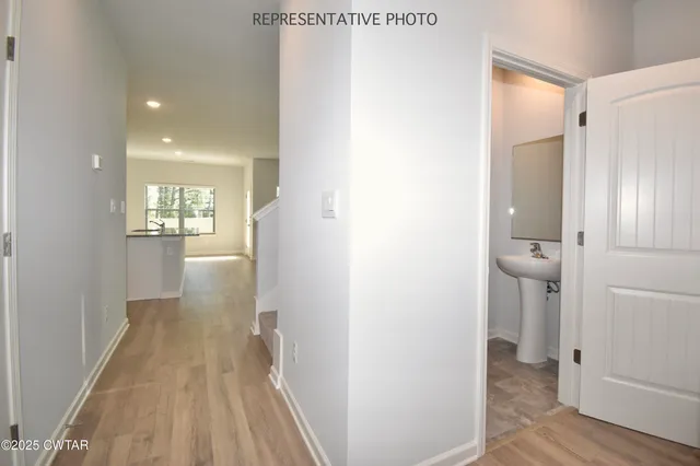 a view of a hallway with wooden floor and a bathroom