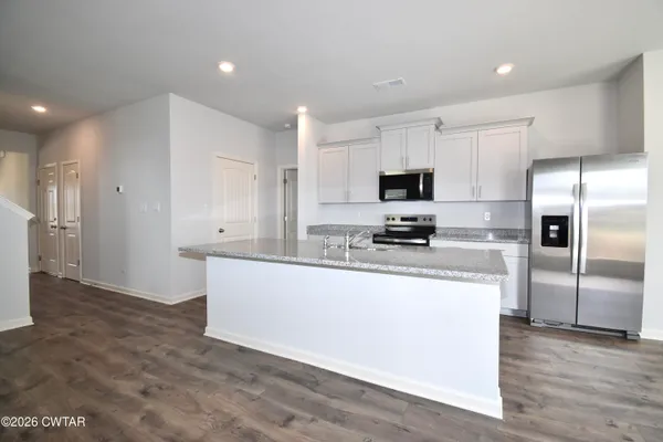 a kitchen with granite countertop a refrigerator and a stove top oven
