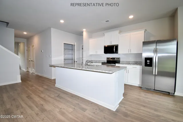 a large kitchen with stainless steel appliances granite countertop a stove a sink and a refrigerator