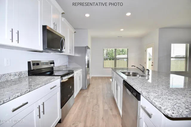 a kitchen with stainless steel appliances granite countertop a sink stove microwave and cabinets