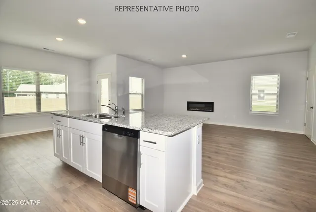 a kitchen with stainless steel appliances granite countertop a stove a sink and white cabinets with wooden floor