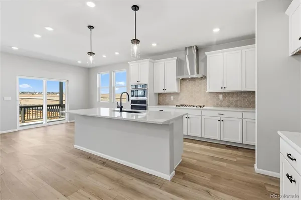 a kitchen with stainless steel appliances granite countertop a sink a stove a refrigerator cabinets and a wooden floor
