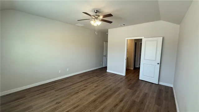 an empty room with wooden floor and a ceiling fan