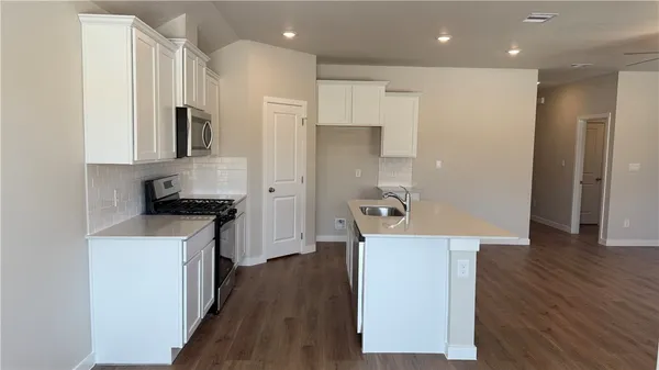 a kitchen with a refrigerator a sink and wooden floor