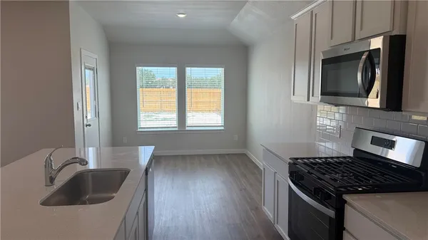 a kitchen with granite countertop a sink stove and cabinets