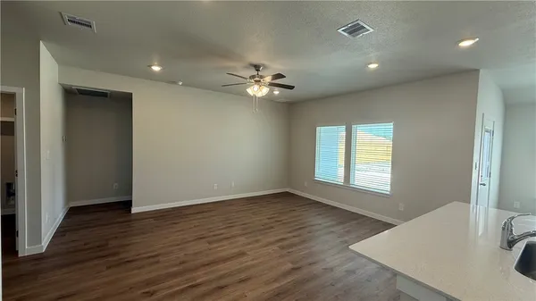 an empty room with wooden floor and a ceiling fan