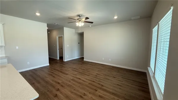 an empty room with wooden floor and chandelier fan