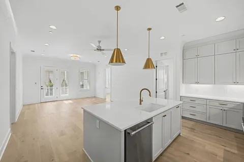 an empty room with wooden floor ceiling fan and windows