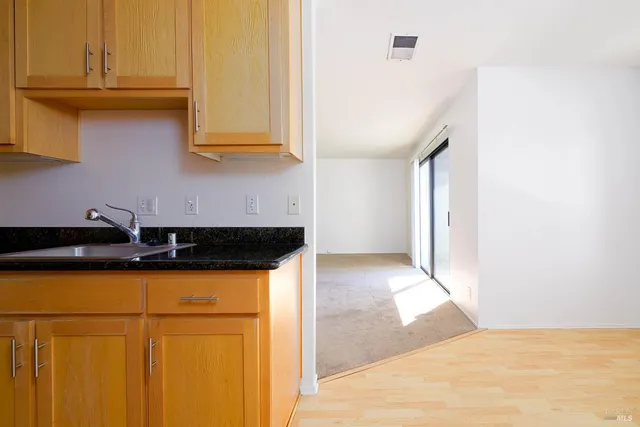 a view of a kitchen with wooden floor and cabinets