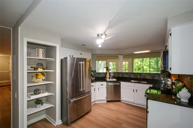 a kitchen with stainless steel appliances granite countertop a refrigerator a sink dishwasher a kitchen island with wooden floor and cabinets