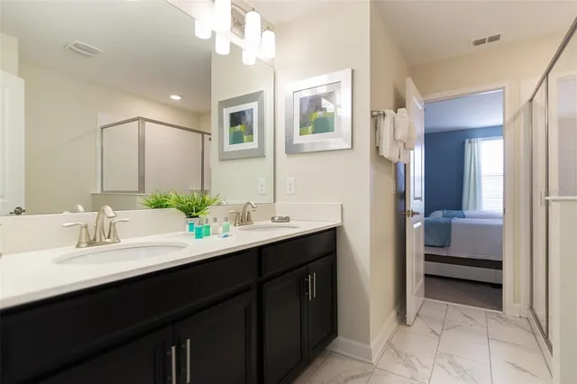 a en suite bathroom with a double vanity sink a mirror and next to a window