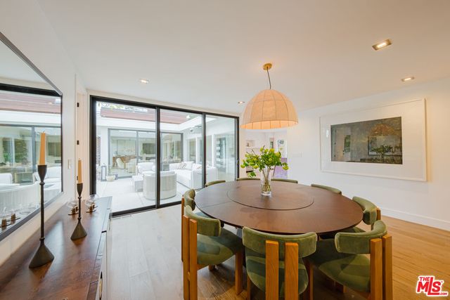 a large white kitchen with kitchen island a stove a sink a refrigerator and white cabinets with wooden floor