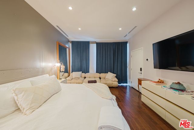 a bedroom with a bed and a dresser with wooden floor