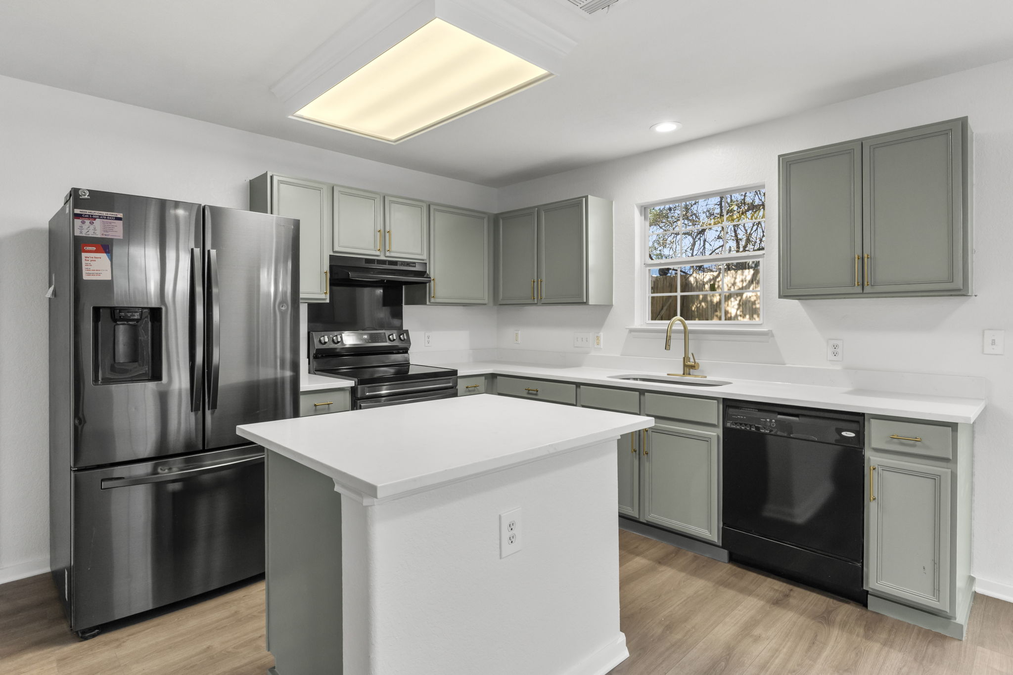 2110 Nogales Trail Austin, TX 78744 - Photo 12 of 36 Kitchen with stainless steel fridge with ice dispenser, black dishwasher, light countertops, electric range oven, and gray cabinetry