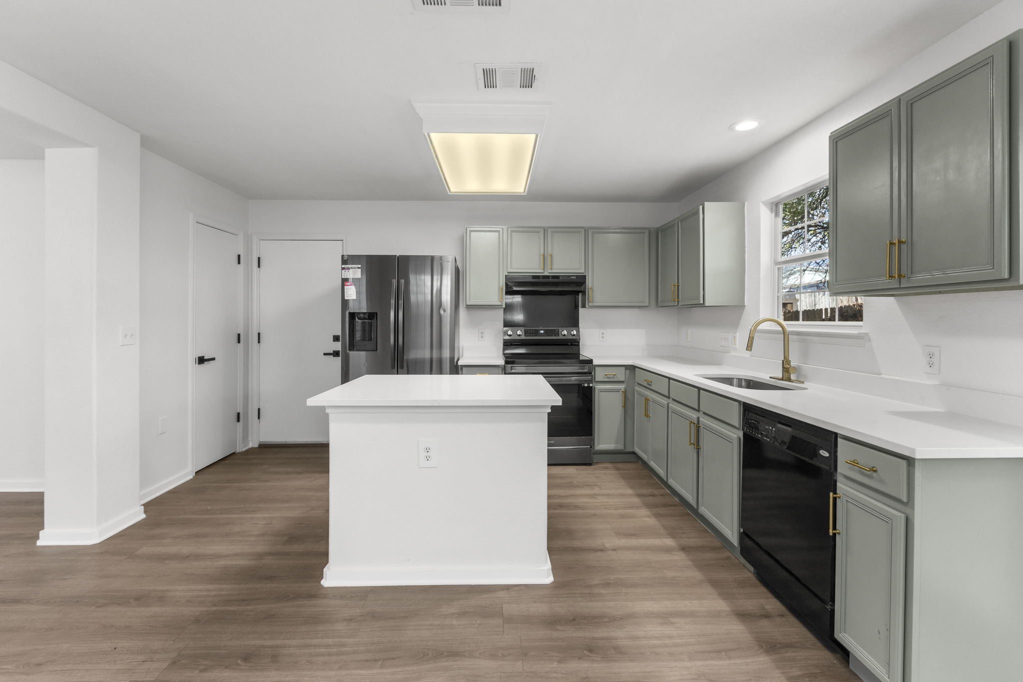 2110 Nogales Trail Austin, TX 78744 - Photo 10 of 36 Kitchen featuring a kitchen island, black appliances, gray cabinets, dark wood-style floors, and recessed lighting