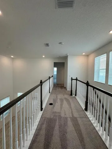a view of a hallway with wooden floor and stairs
