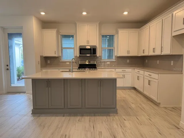 a large kitchen with stainless steel appliances granite countertop a stove a sink and white cabinets