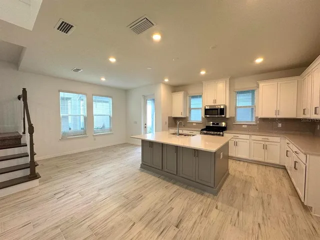 a large kitchen with stainless steel appliances granite countertop a lot of counter space and wooden floors