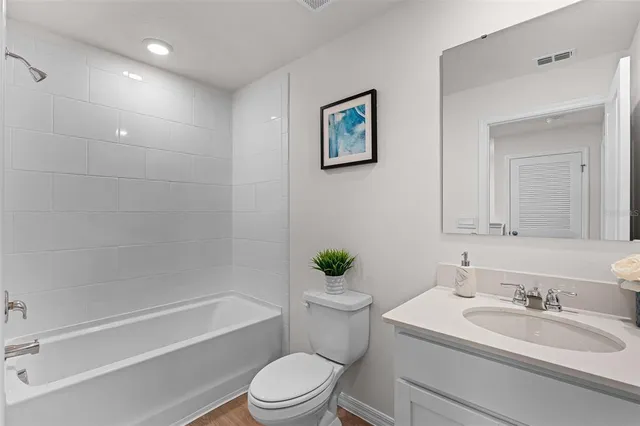 a bathroom with a bathtub shower sink vanity mirror and toilet