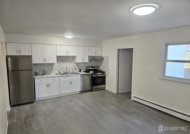 a kitchen with granite countertop white cabinets and stainless steel appliances
