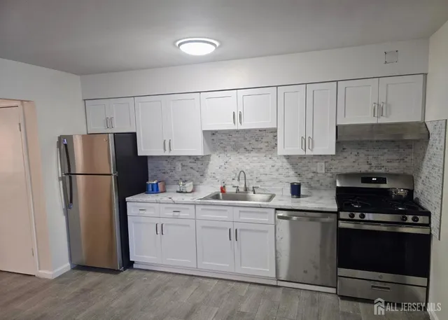 a kitchen with a sink a refrigerator and cabinets