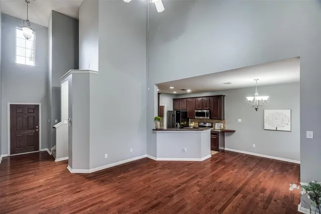 an empty room with wooden floor and a kitchen