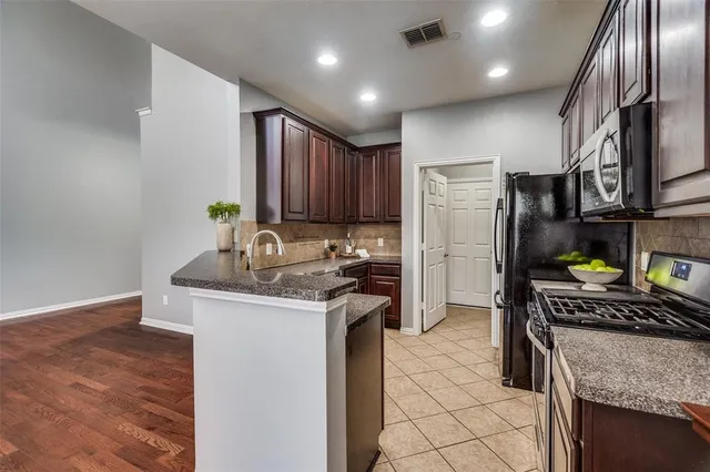 a kitchen with stainless steel appliances granite countertop a stove top oven a refrigerator a sink and dishwasher
