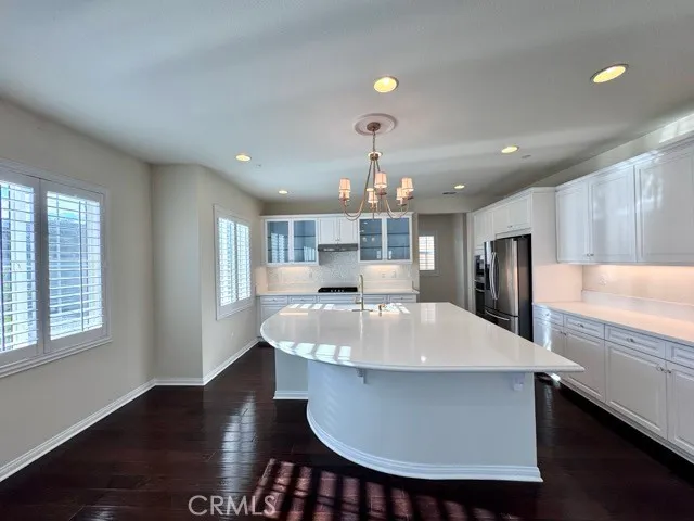 a large kitchen with kitchen island a stove a refrigerator a sink a dining table and chairs with wooden floor