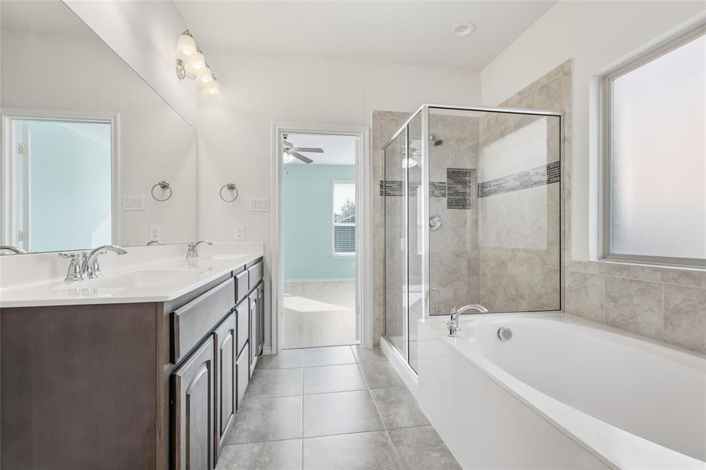 11301 Golden Ridge Lane Haslet, TX 76052 - Photo 20 of 35 a bathroom with a granite countertop sink a mirror bathtub and shower