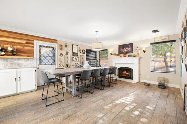 a dining hall with stainless steel appliances kitchen island granite countertop a dining table chairs and a refrigerator