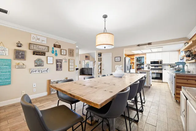 a kitchen with stainless steel appliances a stove a sink dishwasher a refrigerator white cabinets and wooden floor next to a window