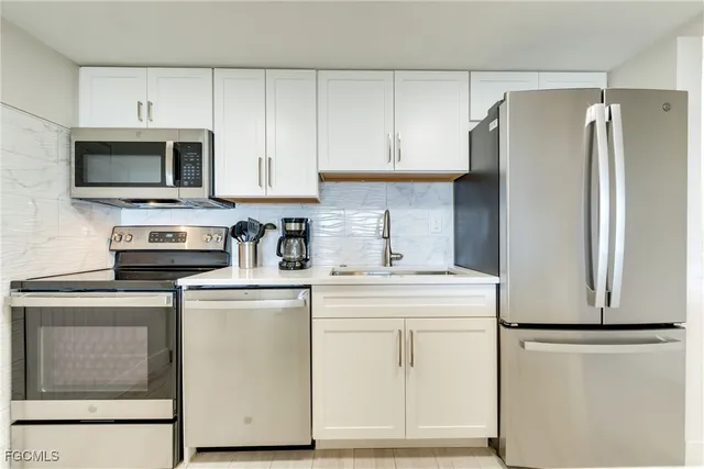 a kitchen with cabinets stainless steel appliances and a refrigerator