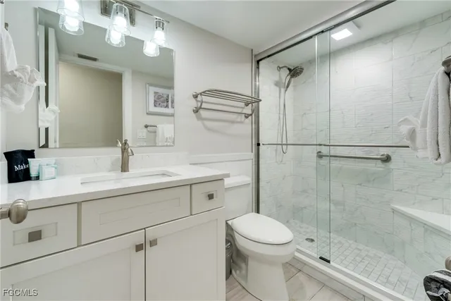a bathroom with a shower sink vanity mirror and toilet