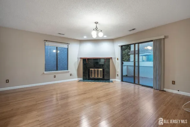 an empty room with wooden floor fireplace and windows