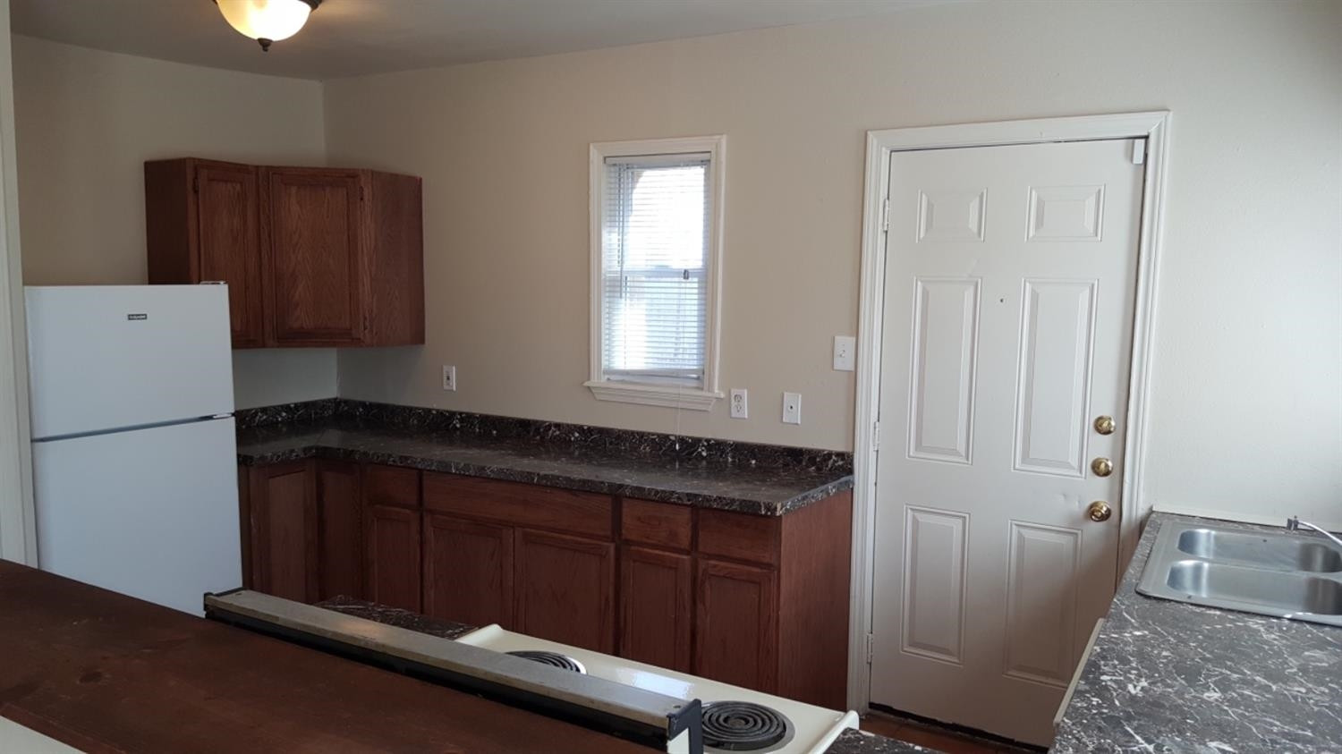 1807 18th Street Lubbock, TX 79401 - Photo 25 of 27 a kitchen with a refrigerator and wooden cabinets