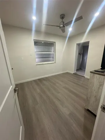 an empty room with wooden floor cabinet and windows
